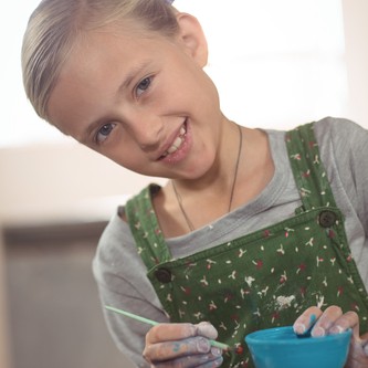 Portrait of smiling girl painting on bowl in pottery workshop
